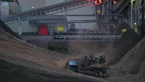 the night shift: a bulldozer clears sawdust at a sawmill under the darkness