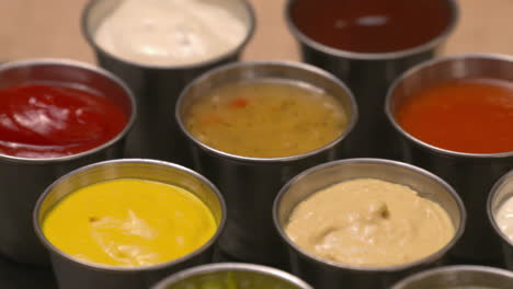 Close-up-selection-of-condiments,-dips,-and-sauces-laid-out-on-a-slate-serving-board