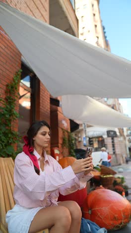 woman taking photo of pumpkins at street market