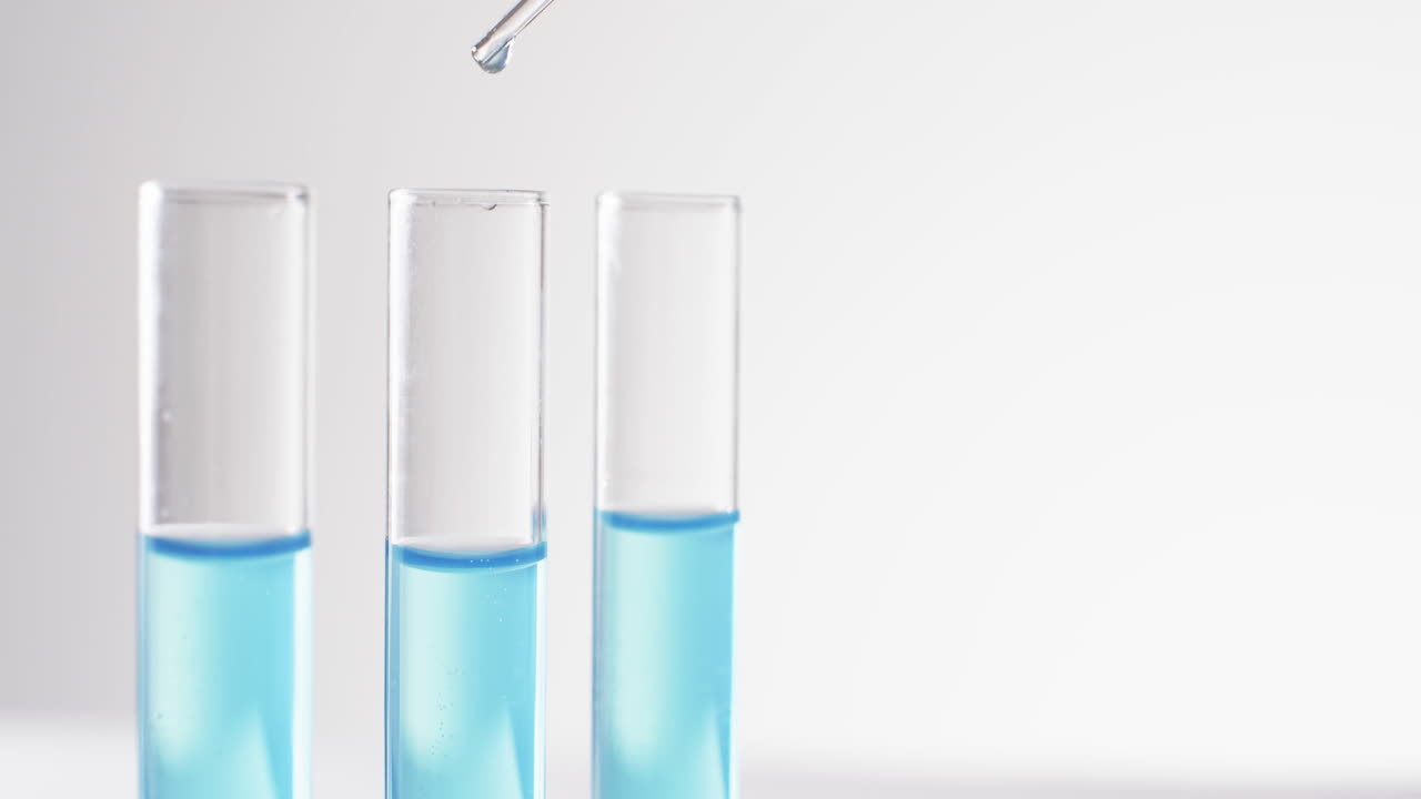 Video of glass laboratory test tubes and pipette with blue liquid and copy space on white background
