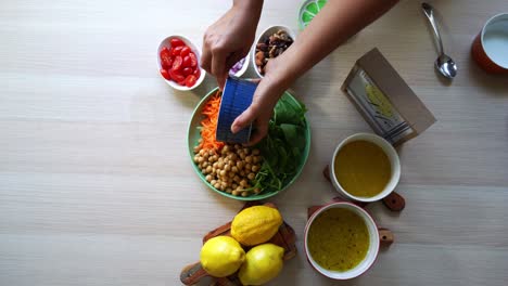 Toma-Aérea-Haciendo-Una-Ensalada-Añadiendo-Garbanzos-Tomates-Zanahorias-Espinacas-Garbanzos-Limones-Cebollas-Nueces-Aderezo-A-La-Vista