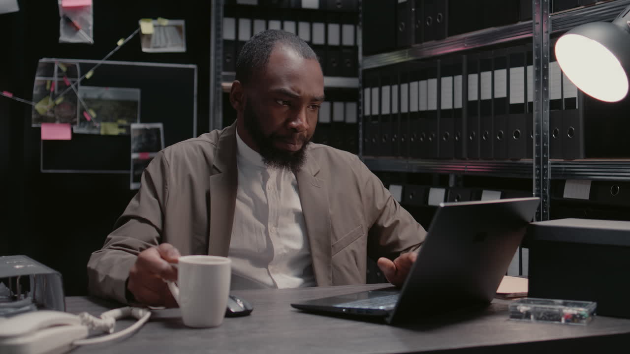 Detective working on laptop with coffee in office