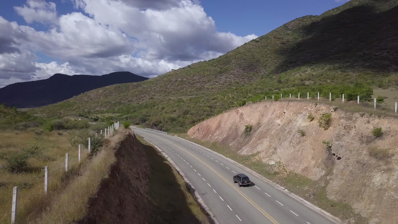 A drone shot following a green SUV as it drives on a highway in Mexico