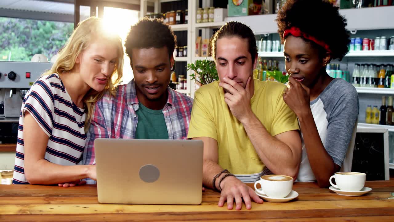 grupo de amigos usando una computadora portátil mientras toman una taza de café