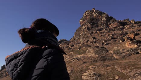 Close-up-of-a-girl-from-the-back-watchin-a-mountain-cliff