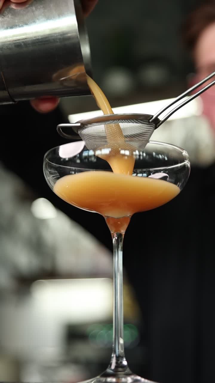 Barman che versa e filtra un cocktail in una coppa
