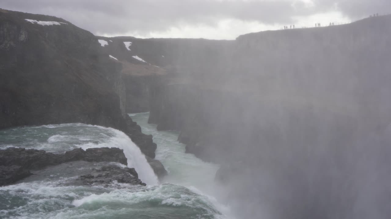 la niebla de la cascada gullfoss en islandia con turistas en el borde, tiempo nublado