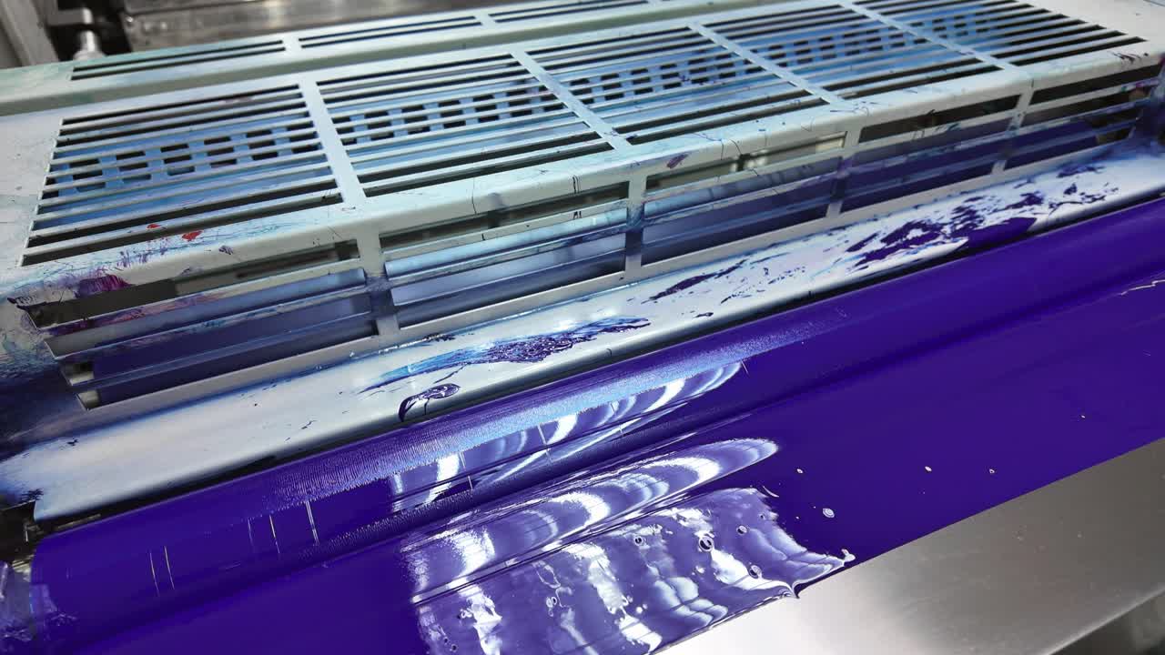 Close up of a printing press roller covered in vibrant blue ink