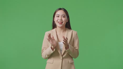 an asian business woman clapping hands impressively on green screen in the studio