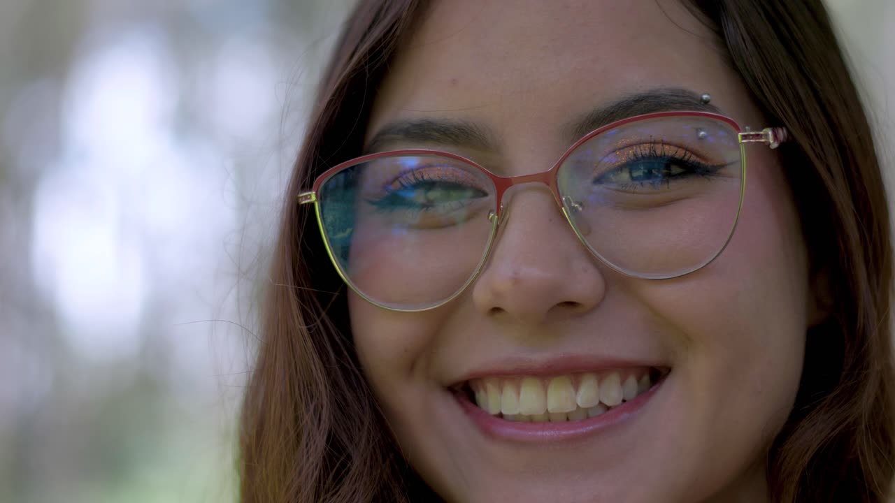 una mujer ecuatoriana con gafas sonríe cálidamente en un cautivador primer plano, emanando encanto latino.