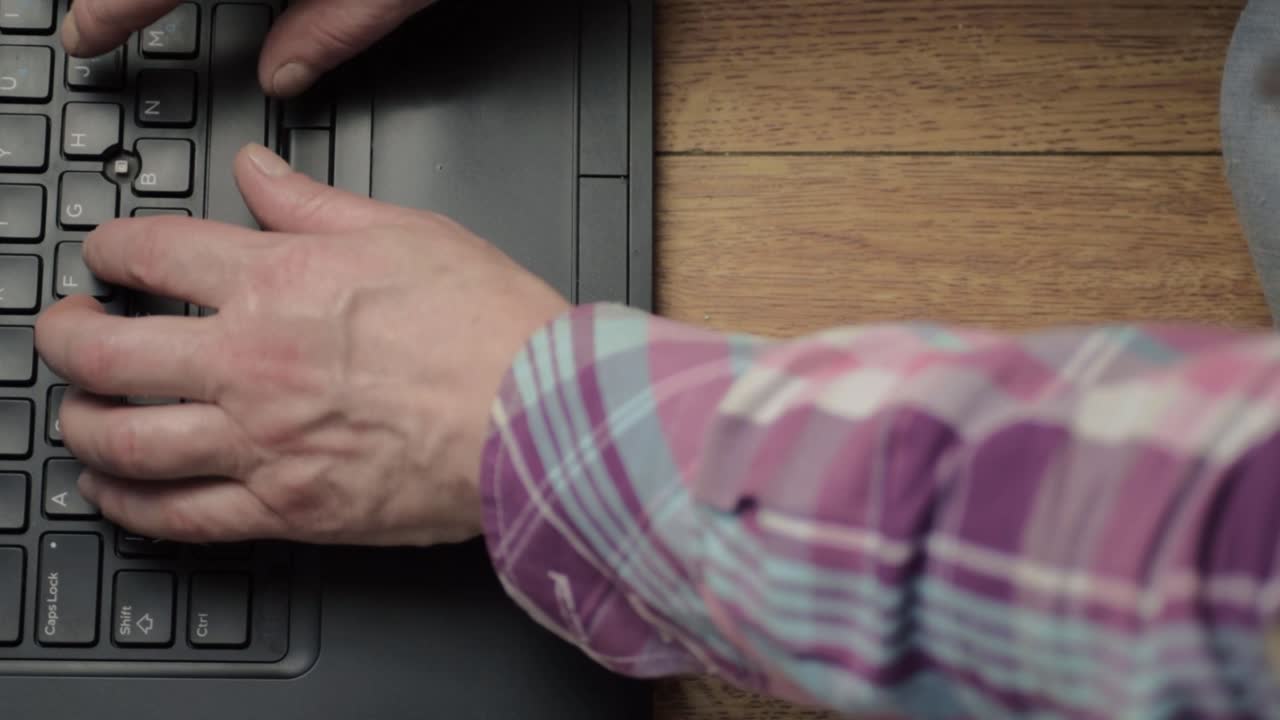 Hands and fingers typing on laptop keyboard flat lay medium shot