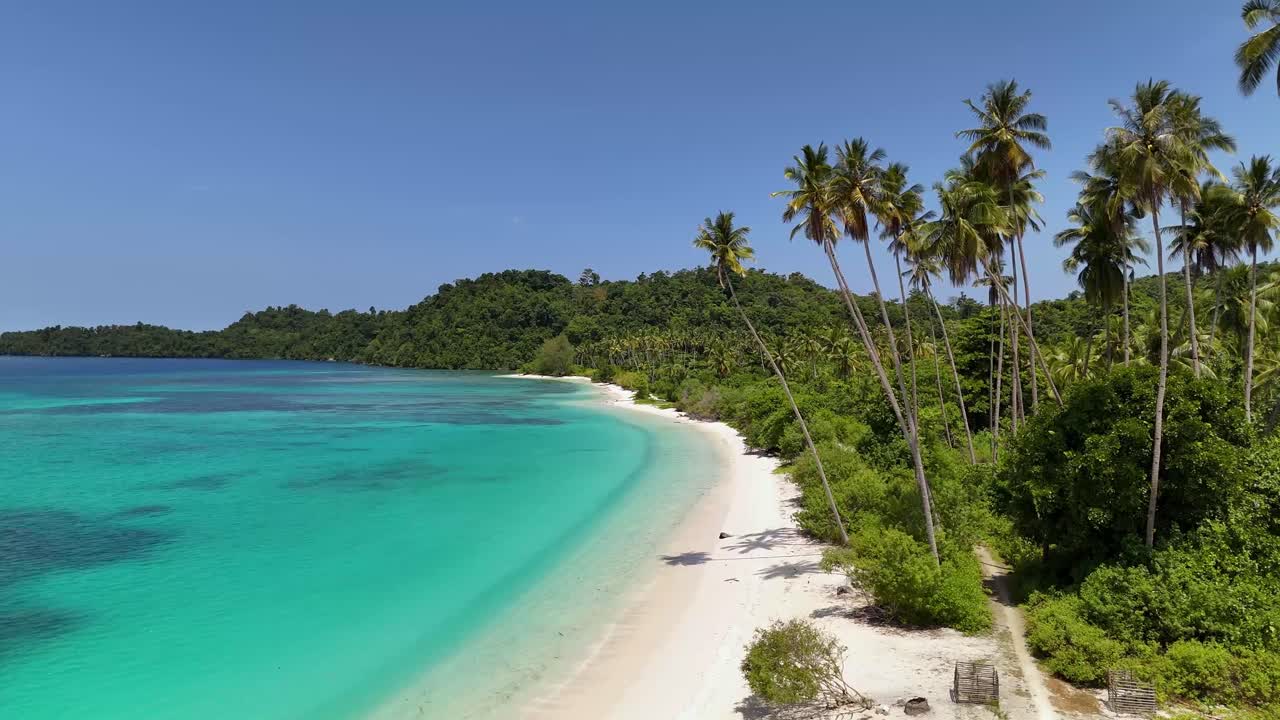 Video drone 4K della Spiaggia di Pompon, circondata da un oceano blu cristallino, lussureggianti paesaggi tropicali verdi e orlata di sabbia bianca nelle Isole Banggai, Sulawesi, Indonesia.