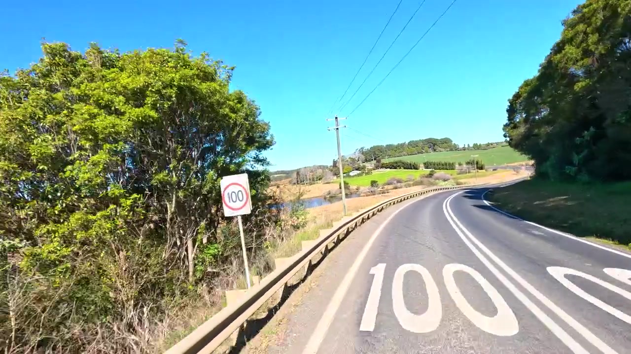 Cámara POV avanza por una carretera rural sinuosa de dos carriles bajo un cielo soleado y brillante