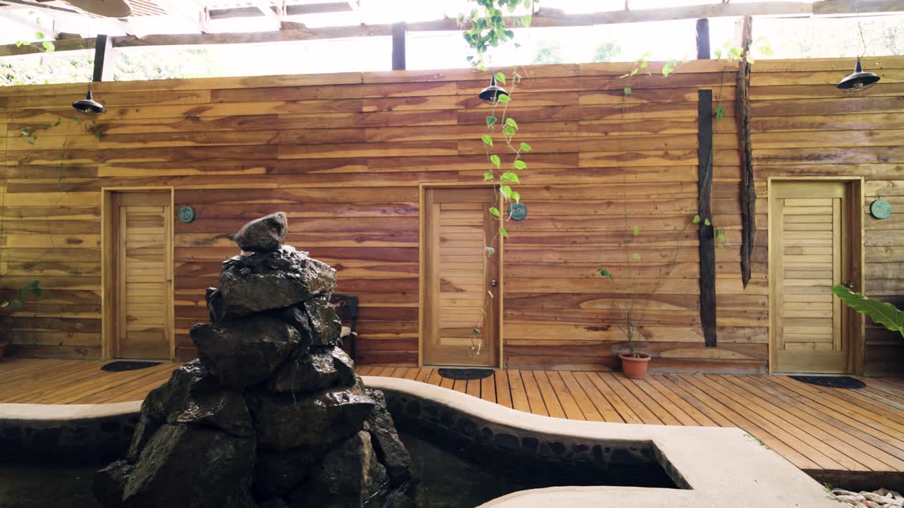 Ulkotilojen spa-alue puisilla seinillä ja kivisuihkulähteellä