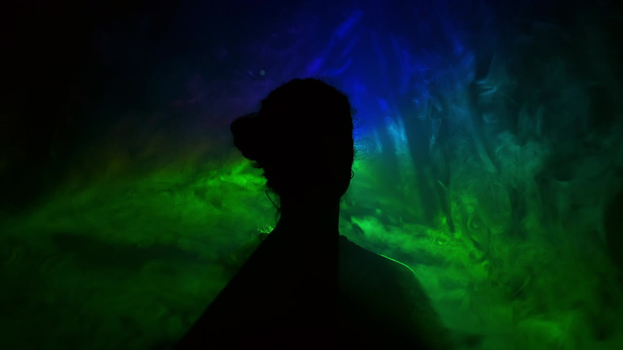 imagen de una niña en un fondo claro de diferentes colores moviéndose en la oscuridad. el humo llena el triángulo con la cabeza de la niña.