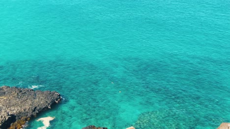 calm turquoise water by rocky shore at makapu’u lookout at oahu, hawaii