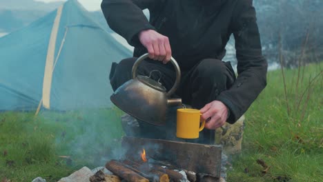 man making cup of coffee solo camping by fire 4k