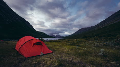 Clouds-rolling-over-the-mountains-and-red-tent-in-Isfjorden,-Norway--Time-lapse