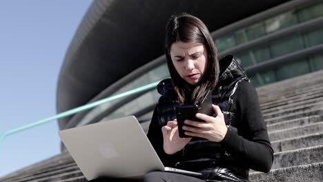 serious woman using laptop and smartphone