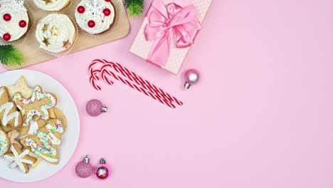 moving plates with delicious christmas cookies and gingerbread cookies and gift on pastel pink theme. stop motion