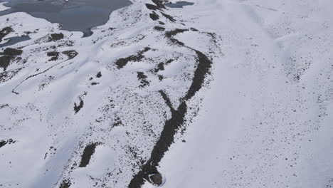 Aerial-rising-and-a-tilting-shot-showing-the-snow-covered-ground-in-a-mountain-valley,-in-Iceland