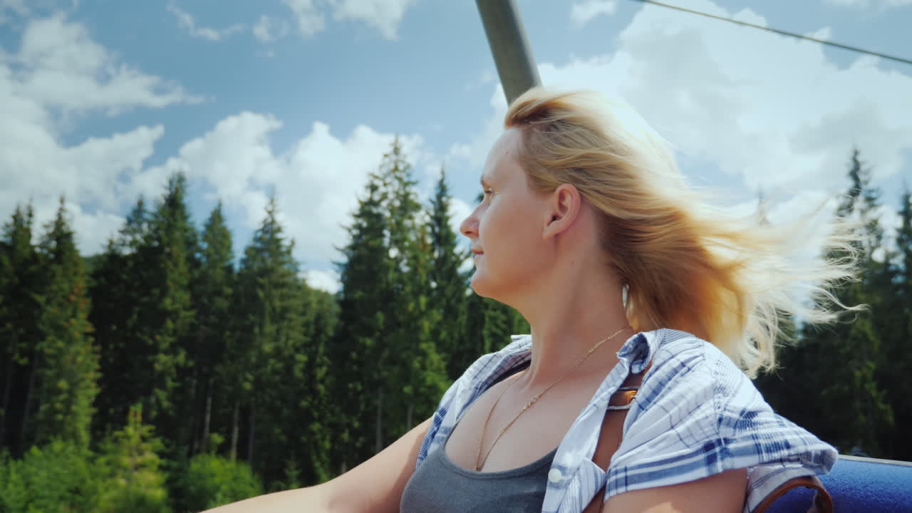 una joven disfruta de un ascensor en el ascensor mira las hermosas montañas y el bosque alrededor de un video de 4k