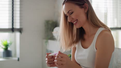 Cheerful-woman-standing-and-holding-a-pregnancy-test.