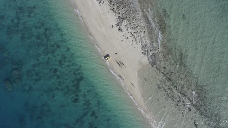 antena descendente de personas y bote inflable en un pequeño islote de coral