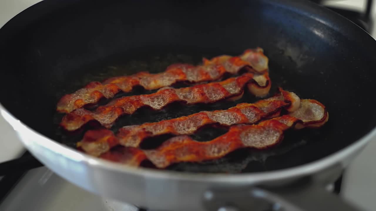 Slices of bacon are grilled on a skillet 1