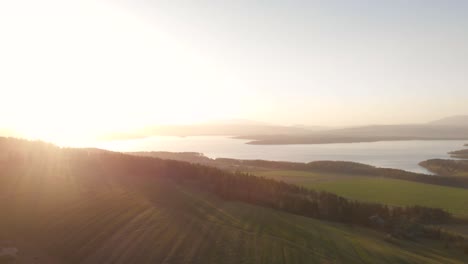 right rotating aerial of beautiful sunflooded landscape with lake in distance and sun glares