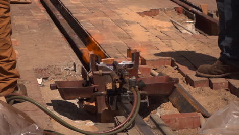 flames burn as workers get ready to weld steel beams for railroad tracks in a city