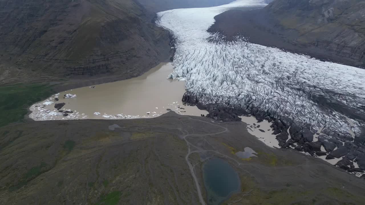 Aerial view getting far from Sv&iacute;nafellsj&ouml;kull glacier, with different ice formations and focus on the empty roads during the summer of Iceland
