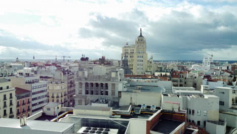 madrid, spain - november 27, 2021: copter flying up along metropolis building wall with masterful stucco work and statues. following aerial madrid scene with residential areas and cloudy sky