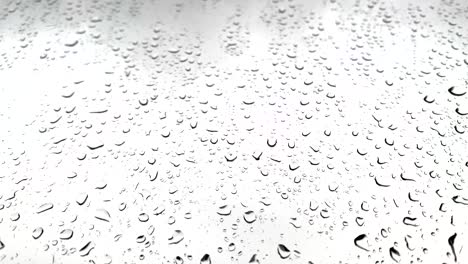 relaxing droplets of rain falling on a large window with a cloudy white sky in the background during lockdown