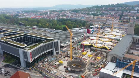 Aerial-of-huge-railroads-and-construction-site-of-main-train-station-Stuttgart-S21-with-cranes-and-construction-workers-descending-over-Stuttgart,-Germany