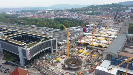 antena de enormes vías férreas y obra de construcción de la estación principal de tren stuttgart s21 con grúas y trabajadores de la construcción que descienden sobre stuttgart, alemania