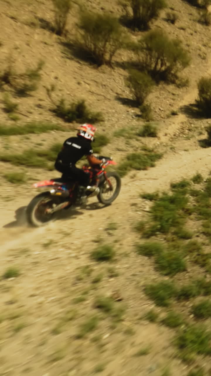 Motorcyclist climbs on machine on low hill fpv. Sportsman rides motorcycle racing at desert highland on sunny day. Dreamlike travel on motorbike
