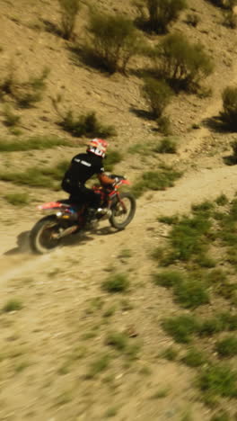 el motociclista sube a la máquina en una colina baja fpv. el deportista monta motocicletas en las tierras altas del desierto en un día soleado. viaje de ensueño en motocicleta