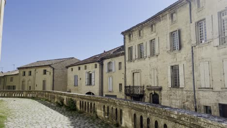 french street row of houses with beautiful historic stone houses in the sun with a small wall in the foreground