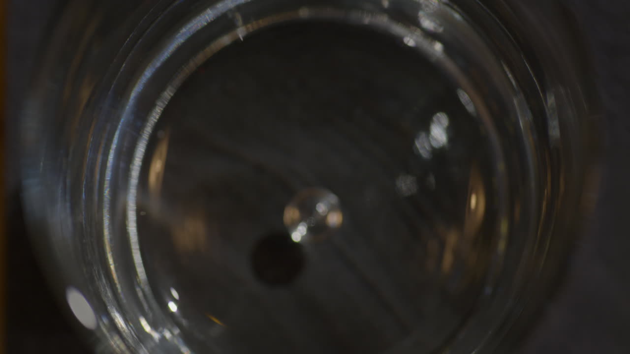 Barman putting Ice Cubes in a glass with Vodka - Top View