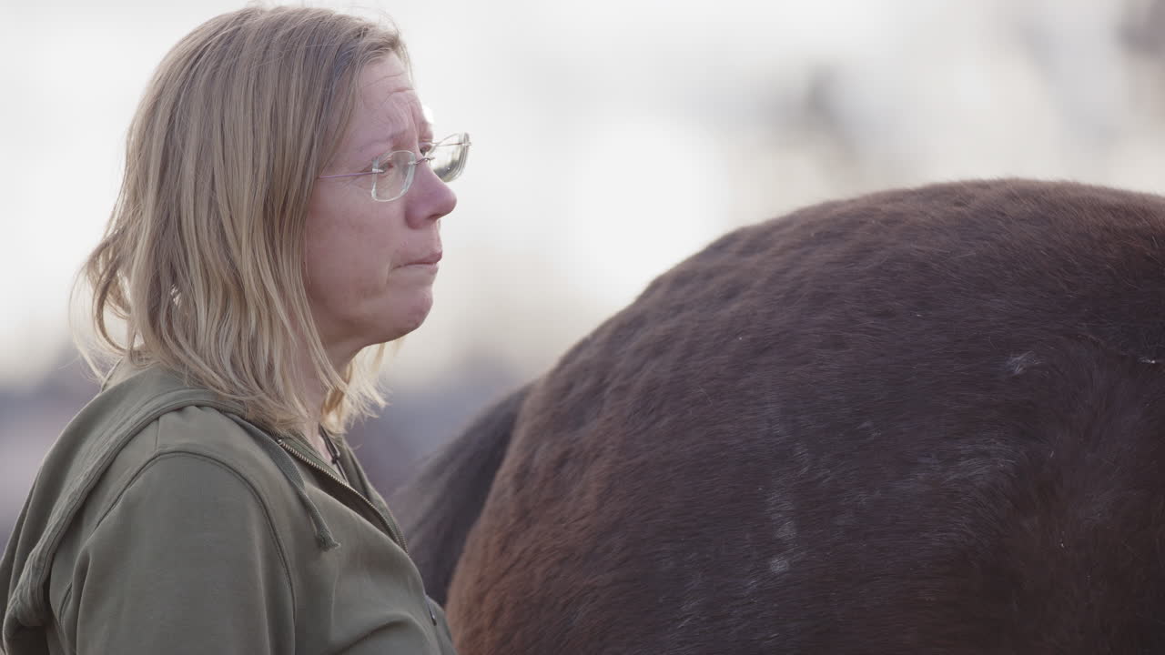 Emotional woman slowly nods head as she processes feelings, equine therapy