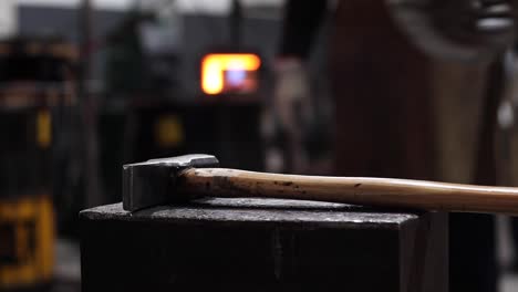 blacksmiths forging hot metal with hammer in workshop