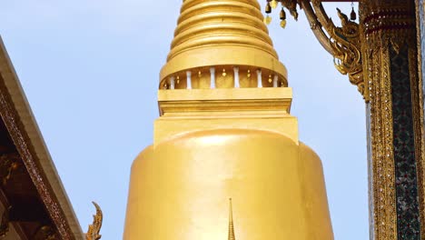 close-up of a golden spire with intricate architectural elements set against a clear blue sky.
