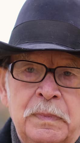 portrait of a grandfather in a hat who adjusts his glasses while standing in an autumn park portrait of a grandfather in a hat who adjusts his glasses while standing in an autumn park