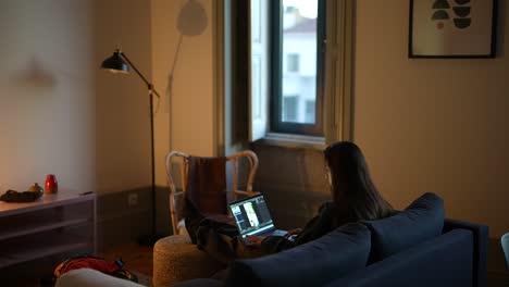 mujer trabajando en una computadora portátil en la sala de estar por la noche