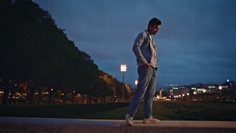 stylish man relaxing evening town park illuminated street lights. guy walking