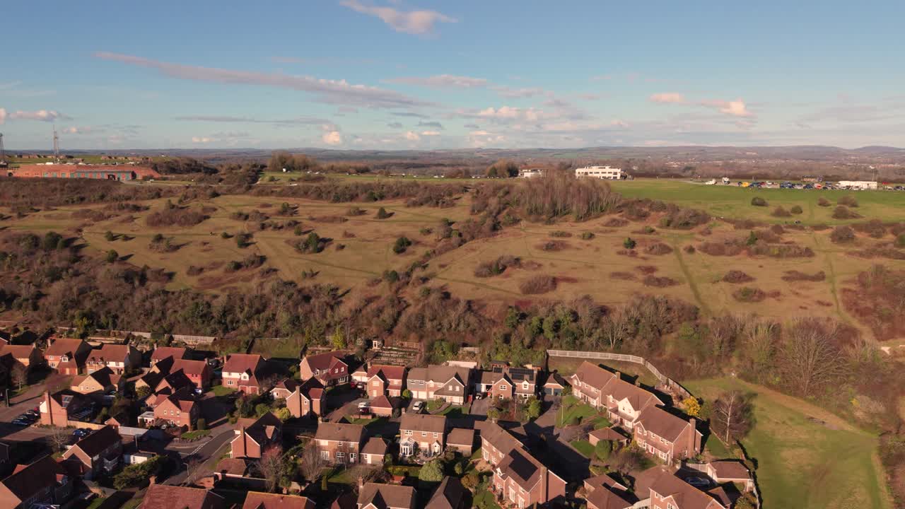Fort Widley Swanick Hill Portsmouth, volo sopra abitazioni e collina superando il forte militare riadattato, guardando nell'entroterra su una campagna ondulata sotto un sole splendente con cielo azzurro e nuvole leggere