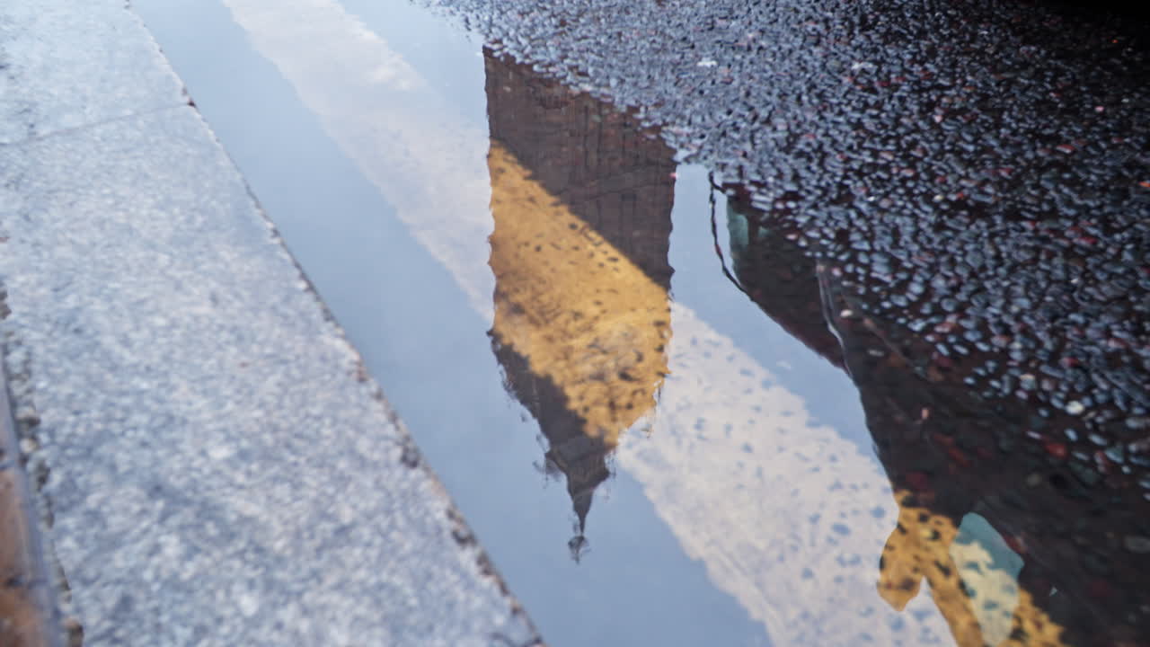Reflection of Big Ben in a puddle on a London street after rain