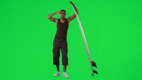 Ethnic-boy-with-a-surfboard-against-green-screen