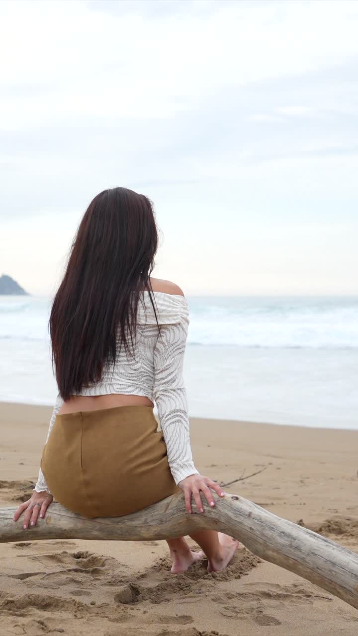 Woman Sitting on Beach Looking at the Ocean